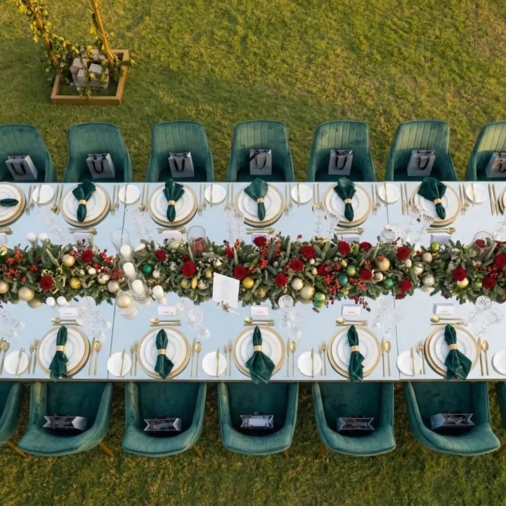 VELVET CHAIR ROYAL GREEN encircles a festive outdoor dining table adorned with elegant tableware and garland, highlighting Party Social&