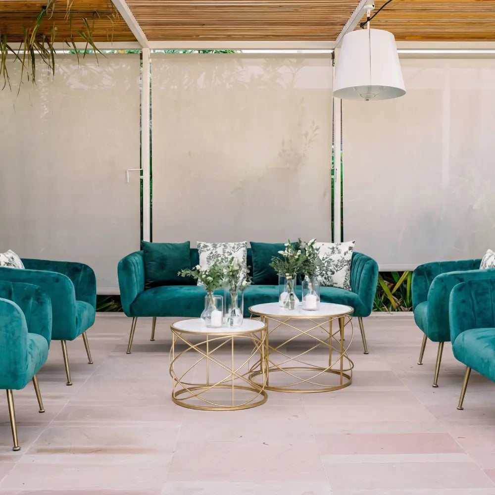 ROYAL GREEN VELVET 3-SEATER with brass-tone legs, perfect for elegant events, surrounded by matching armchairs, coffee tables, and greenery accents in a stylish lounge setting.