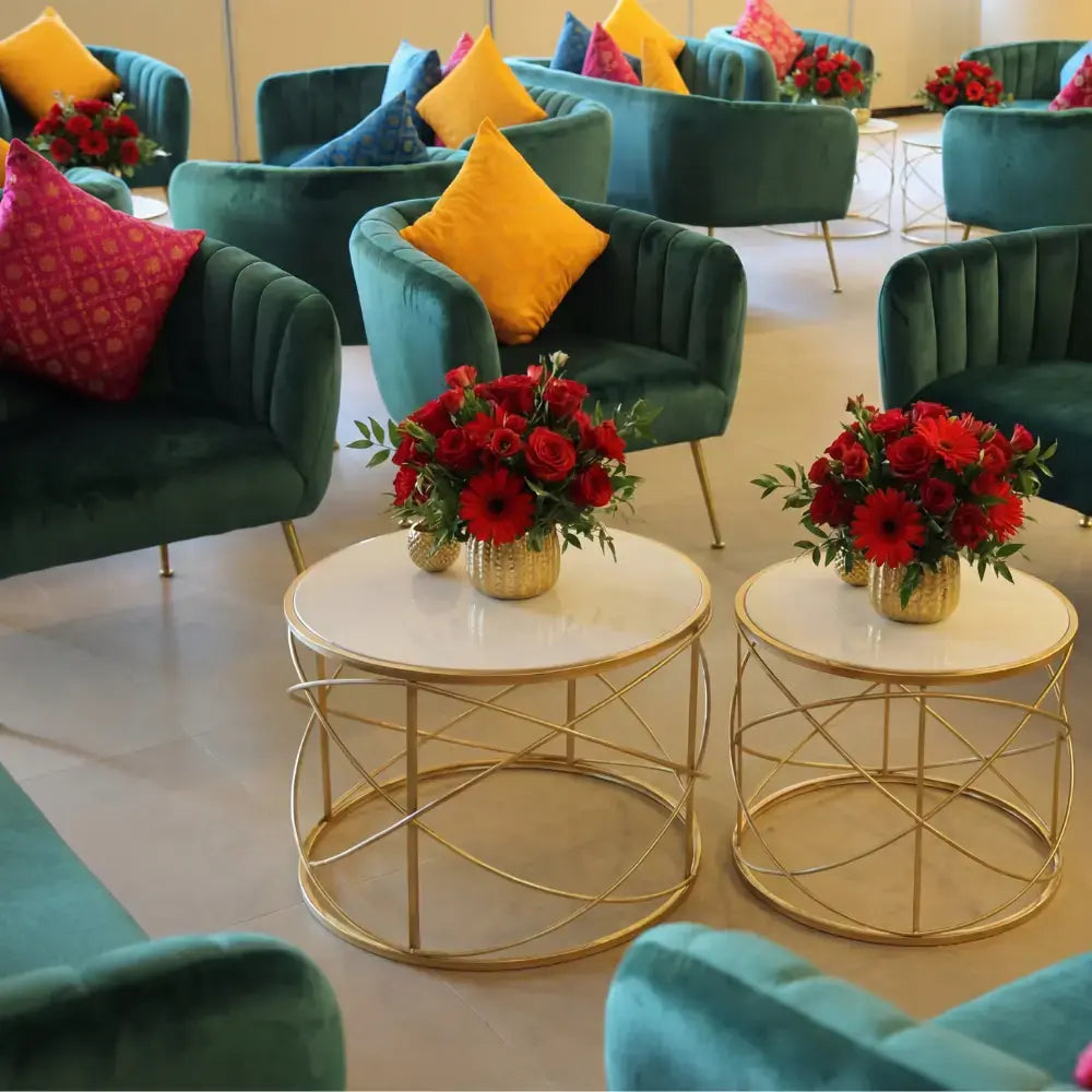 ROYAL GREEN VELVET SINGLE SEATER armchairs arranged in a chic lounge setting with marble tables and vibrant accent pillows, perfect for upscale events.