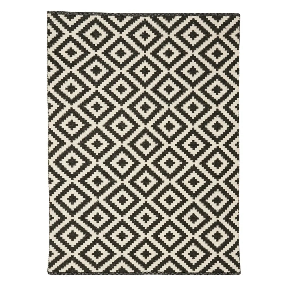 RUG DIAMOND PRINT: Rectangular area rug with a black-and-off-white geometric diamond pattern, ideal for enriching any event setting. Available in large and small sizes.