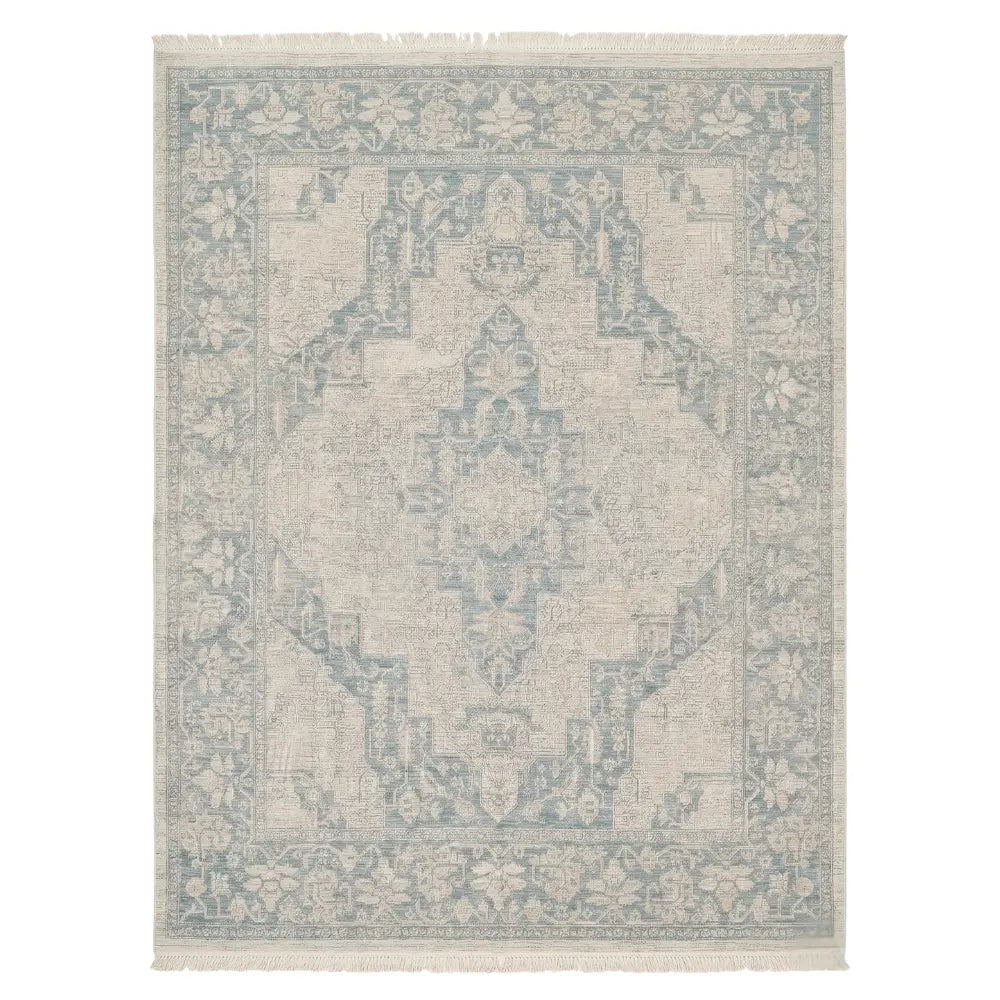 RUG VINTAGE PATTERN: Rectangular rug with a faded medallion design, neutral tones, light blue motifs, and fringe, ideal for adding elegance to event spaces.