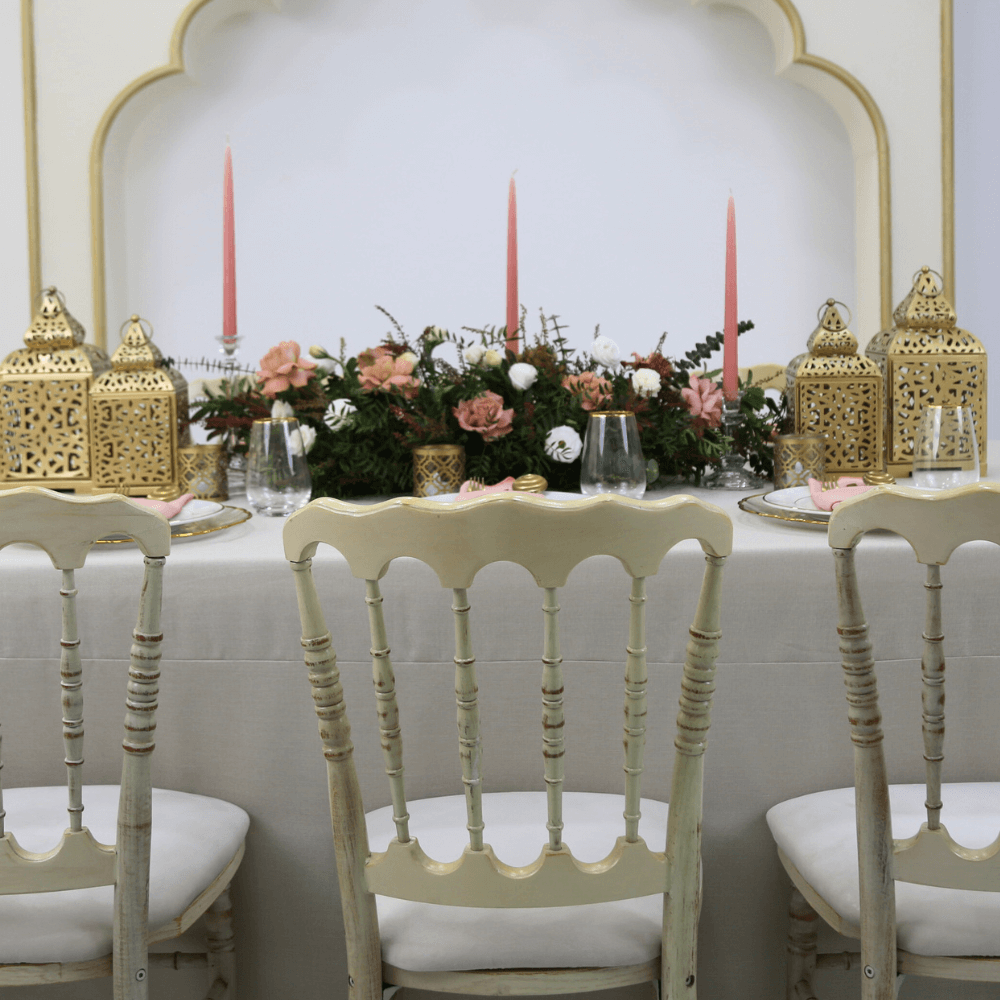 Ramadan Luxe- Dining Setup featuring a flower centerpiece, candles, gold lanterns, and cream wash chairs for 8 guests by Party Social.