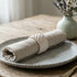 Plated dish with rolled napkin and fork on a wooden table