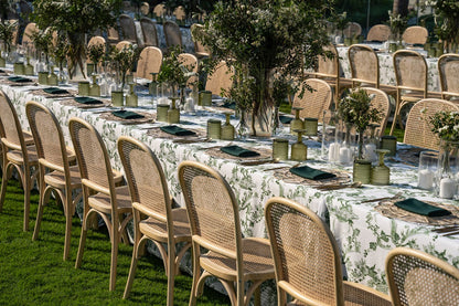 Rattan chairs set around a table, ideal for weddings or corporate events, showcasing their vintage appeal and versatility in outdoor settings.