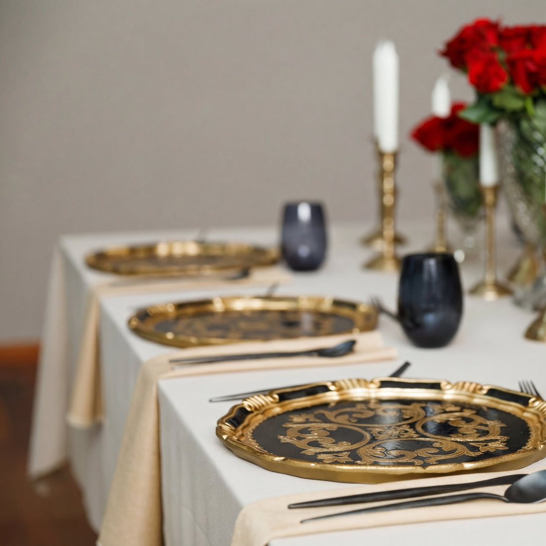 The Midnight Majlis Collection showcases a formal tablescape with gold-patterned charger plates, black flatware, and white taper candles in brass holders, ideal for Ramadan gatherings.