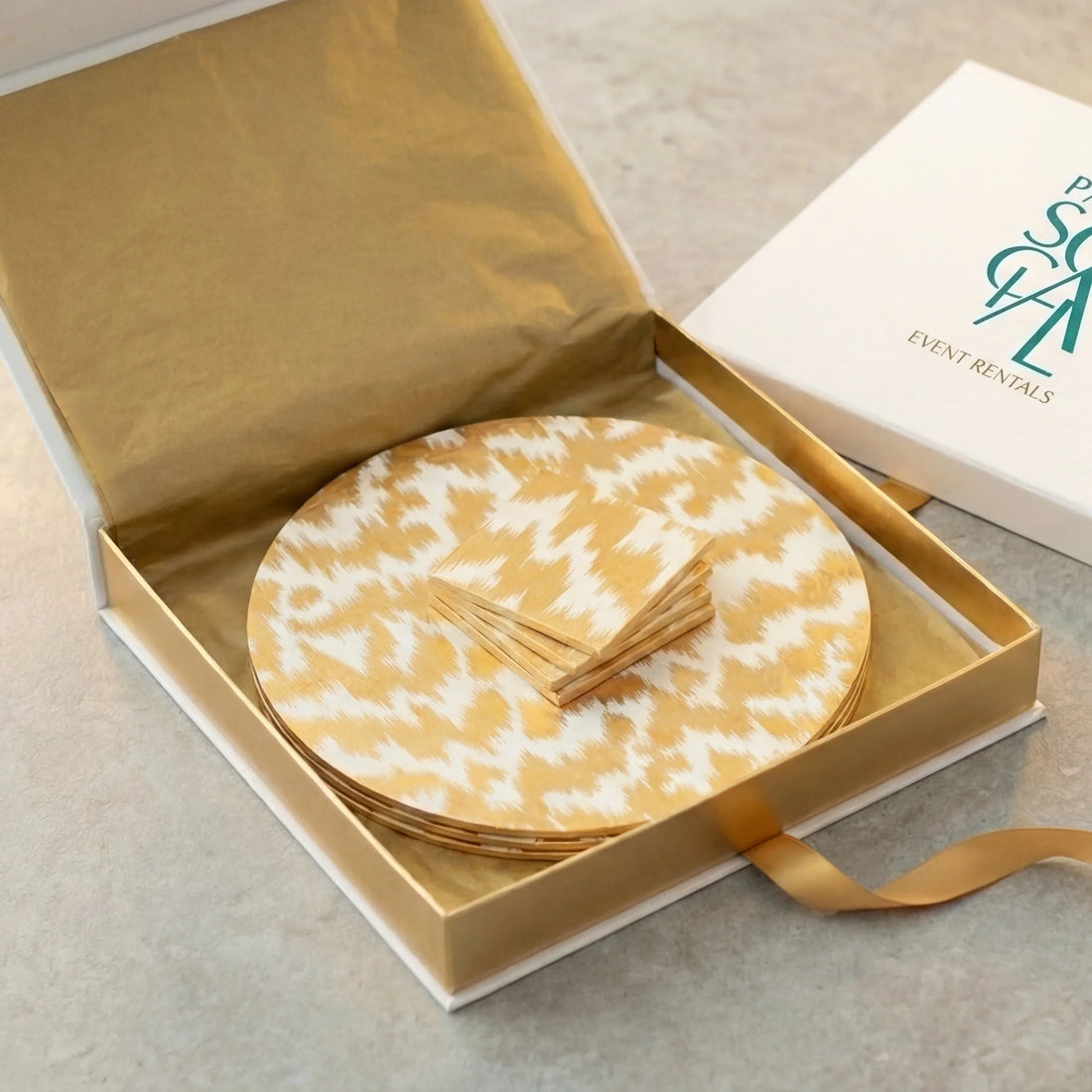 Modern Moiré Gift Set: A gold tissue-wrapped box from Party Social containing decorative gold-and-white patterned placemats and matching napkins, perfect for Ramadan celebrations and luxury gifting.
