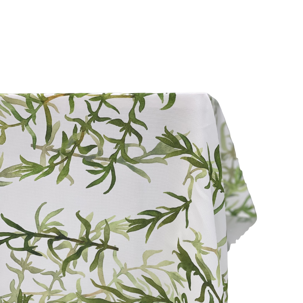 Gardenia Linen Tablecloth featuring a watercolor-style green leafy pattern, draped over a table edge, offering a premium touch for events or dinners.