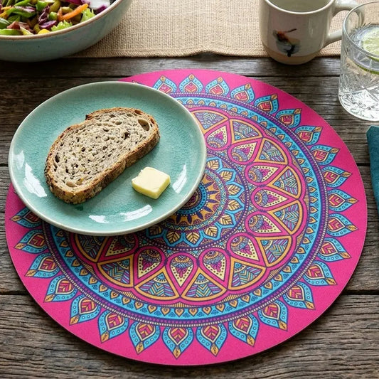 Colorful mandala placemat with a plate of bread and butter, fork, knife, and glass on a wooden table.