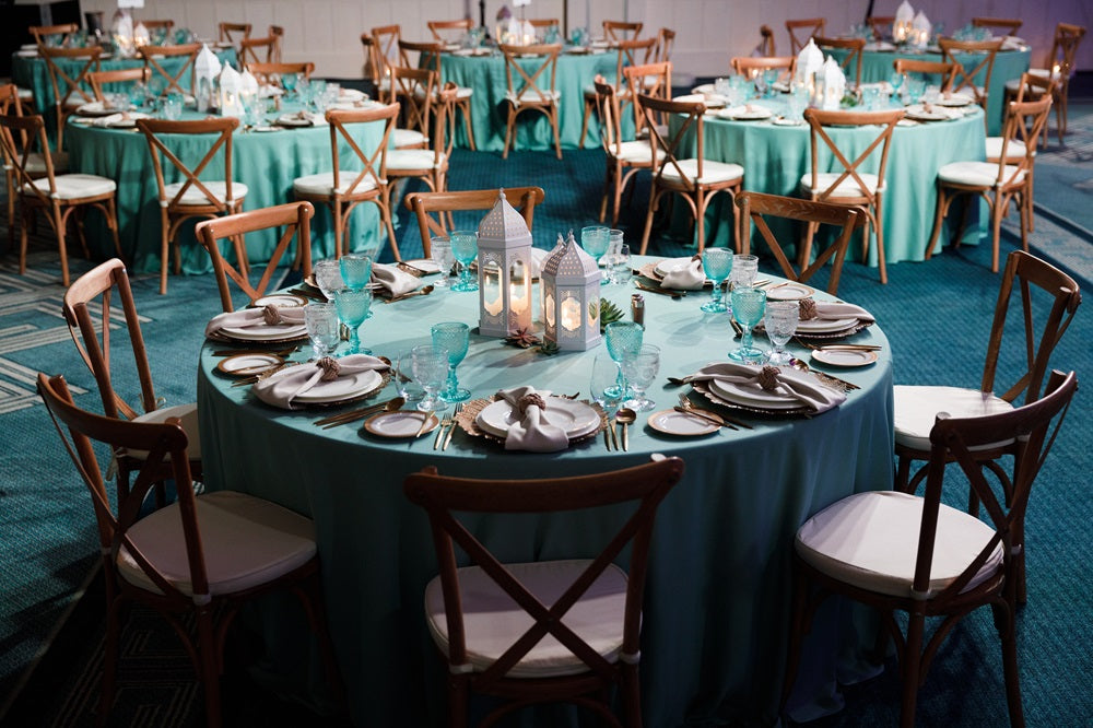 Round Banquet Tables set for a dinner party, seating 6-8 people, perfect for events. Featured with tableware and white cushioned chairs.