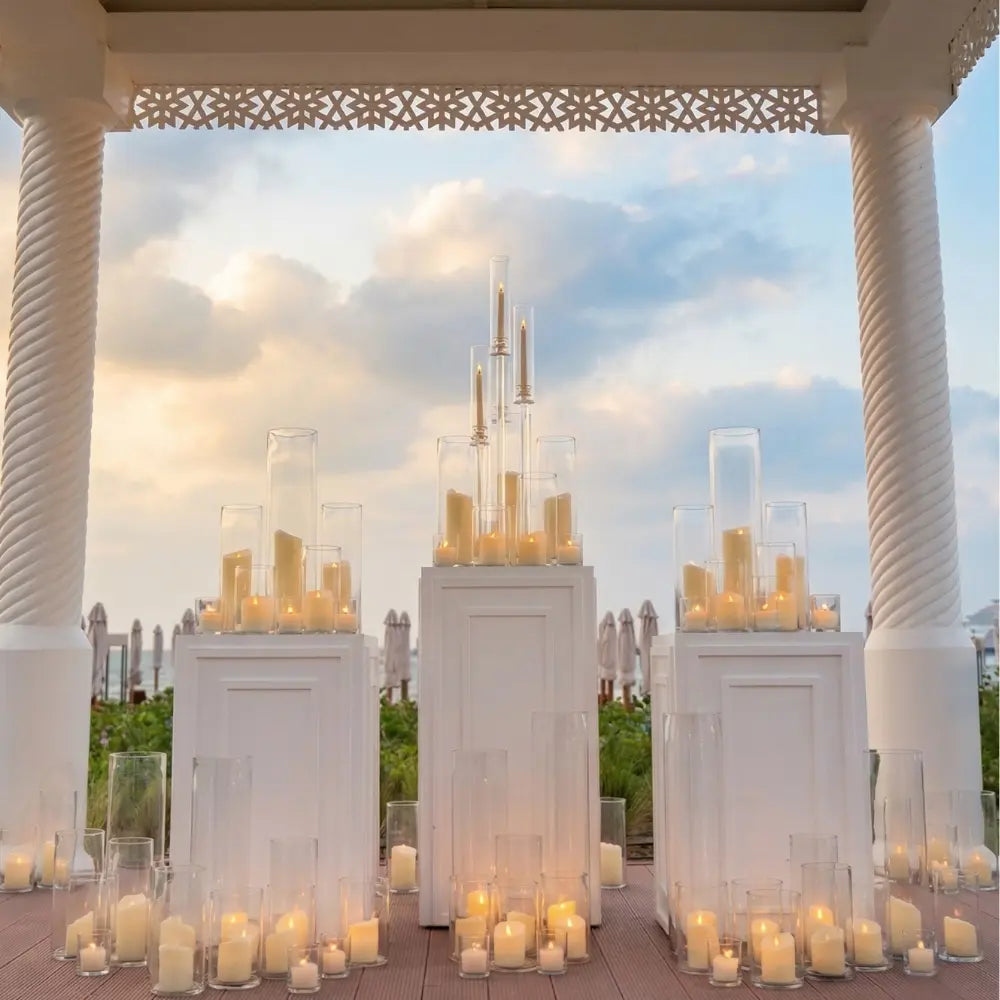 Square Lined Podiums in a beachside gazebo, displaying pillar candles in glass cylinders, ideal for elegant event décor provided by Party Social.