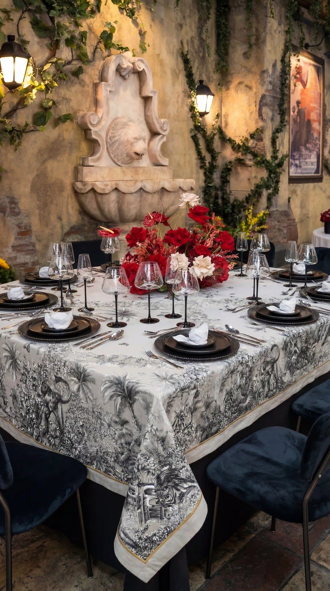 Elegant dining setup featuring the Savannah Toile Linen Tablecloth with intricate pastoral scenes, surrounded by lush floral centerpiece and sophisticated table settings.