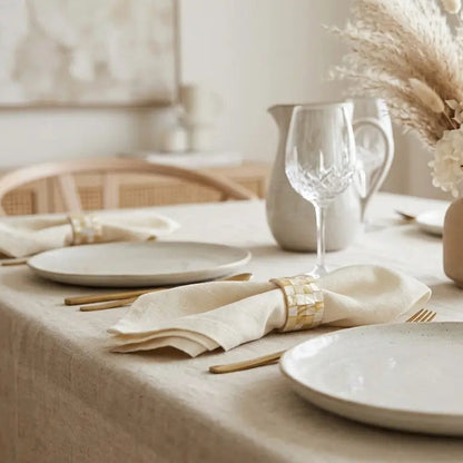 Elegant table setting with white plates, gold cutlery, and decorative elements.