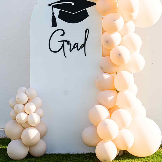 Sweet Soirée Balloon Arrangement featuring a Grad backdrop with customizable prints, flanked by balloon columns, perfect for elevating any graduation celebration.