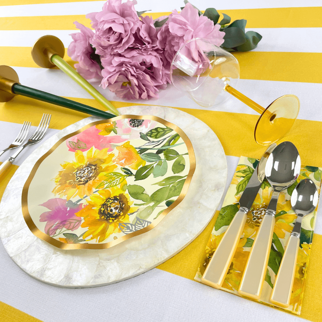 Yellow Stripe Linen Tablecloth on a table set with a floral plate, silverware, and pink flowers, enhancing a dining setup.