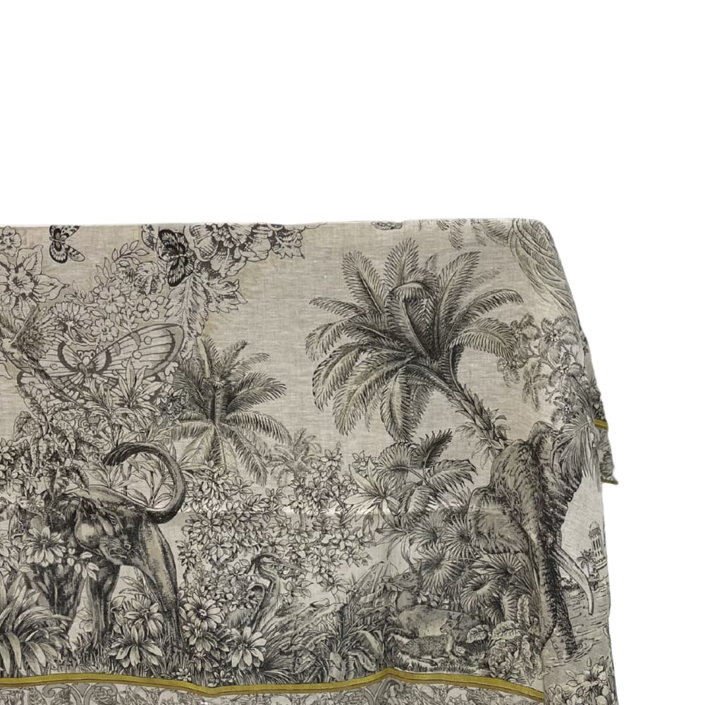 Savannah Toile Linen Tablecloth showcasing a detailed black-and-white toile jungle scene with elephants, palm trees, and a decorative border, perfect for elegant dining settings.