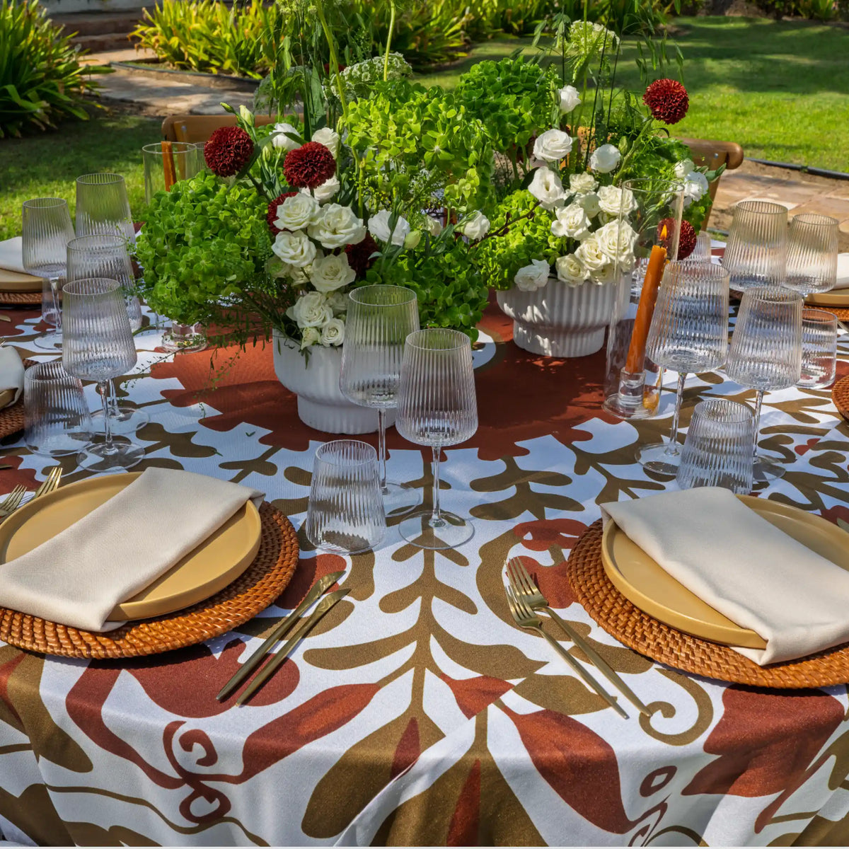 uscan Terracotta Tablecloth. Featuring a bold botanical print in rich terracotta and earthy olive tones, this statement linen creates an effortlessly elevated setting inspired by Mediterranean dining