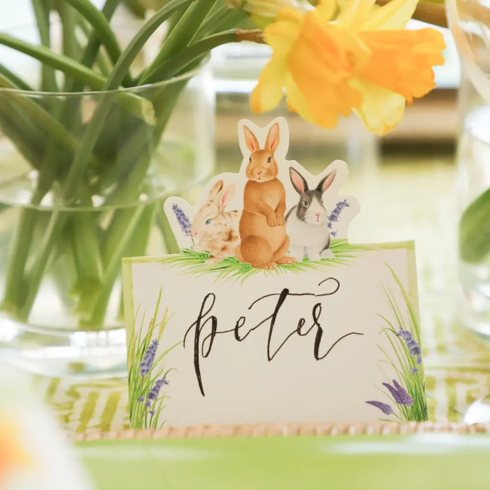 Place card with rabbits and 'Peter' text, surrounded by flowers and greenery