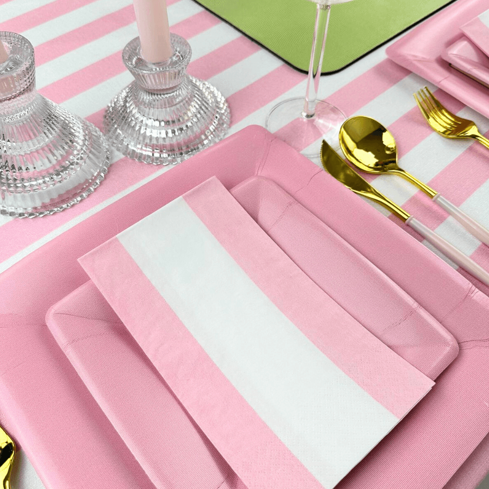 Bandol Stripe Paper Guest Towel Napkins - 15 Per Package displayed with cutlery on a pink and white striped table setting, emphasizing eco-friendly design and artistic flair for special occasions.