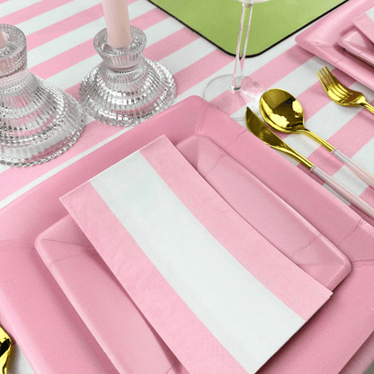 Bandol Stripe Paper Guest Towel Napkins - 15 Per Package displayed with cutlery on a pink and white striped table setting, emphasizing eco-friendly design and artistic flair for special occasions.