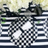 Round Shell Patterned Placemat in Black & White Color, 1 each, displayed on a table with black and white plates, a folded napkin, and a vase with white flowers.
