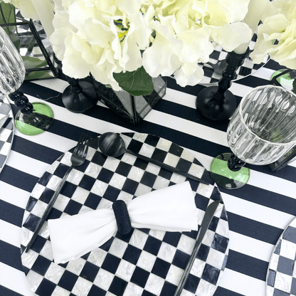 Simple Black Cutlery Set of 4 displayed in an elegant black and white table setting with floral centerpiece.