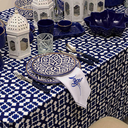 Marrakesh Linen Tablecloth displayed on a table set with blue and white plates, utensils, and glassware. Perfect for enhancing dinner parties and special occasions.