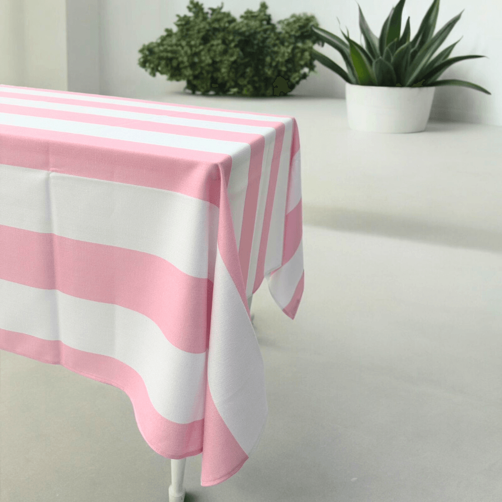 Pink Stripe Linen Tablecloth on a table with a potted plant, enhancing any event’s décor with a premium, reusable polyester linen feel.