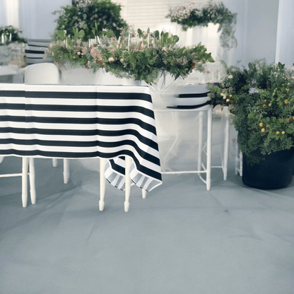 Black &amp; White Linen Tablecloth on a table with striped pattern, surrounded by chairs and a plant, perfect for parties and events.