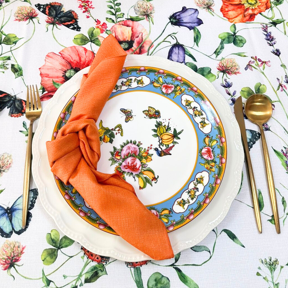 FLORAL PATTERNED PLATES with elegant floral design, set with an orange napkin and spoon, ideal for enhancing party and event table settings.