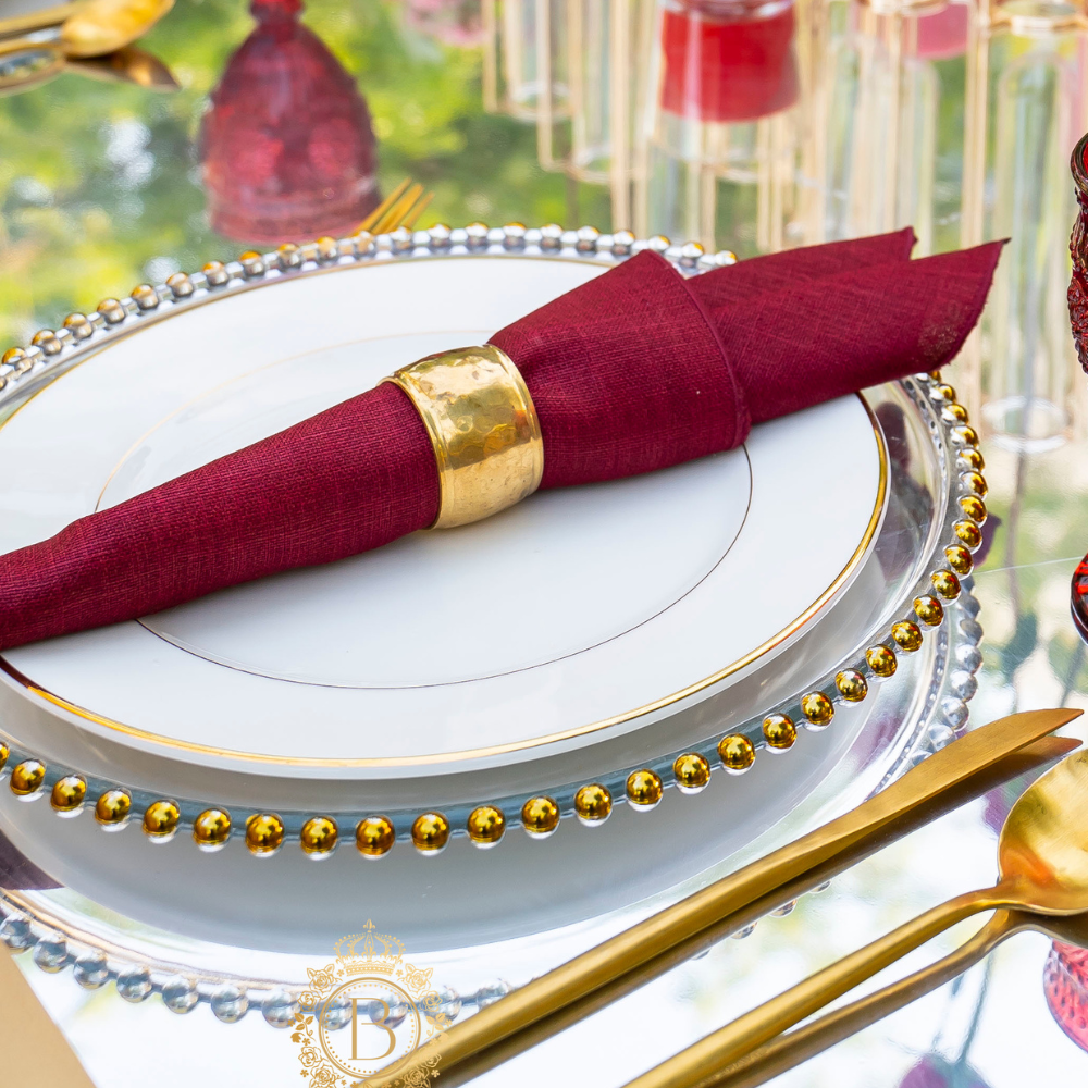 Hammered dome napkin ring on a plate, showcasing its round, textured design suitable for elegant tablescapes, available in gold or silver.