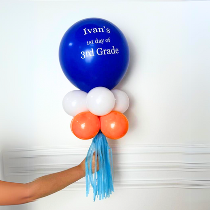 Hand holding a Personalised Back to School Balloon Wand, featuring a large balloon with custom text and smaller balloons, ideal for memorable first-day photos.