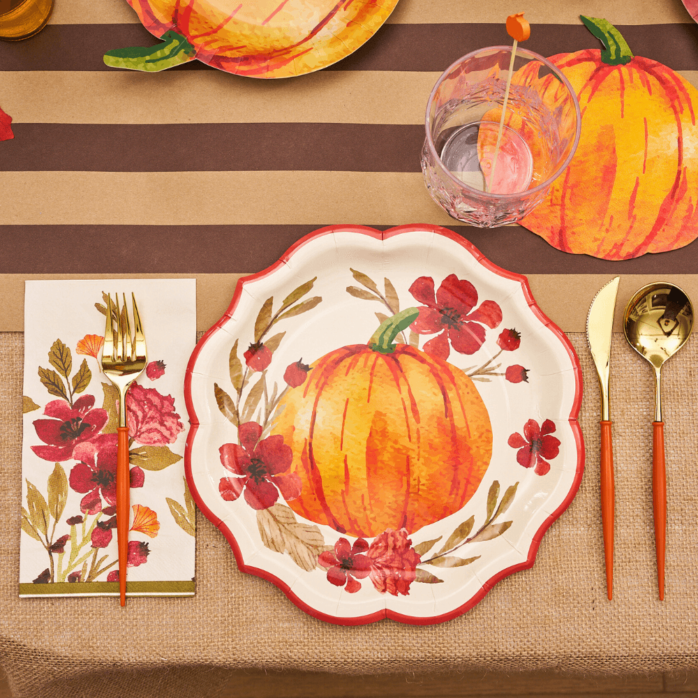 Autumn Foliage Dinner Plate on table with utensils, featuring a painted pumpkin design. Ideal for festive gatherings, sold as 8 per package.