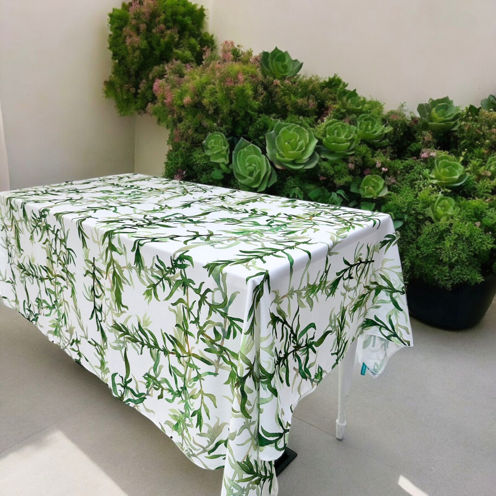 Gardenia Linen Tablecloth (1pc) on a table with white tablecloth and green plants, adding elegance to dining settings.