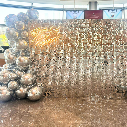 Sequin Wall backdrop featuring shiny silver balls, ideal for events like weddings and parties. Perfect for pairing with floral or balloon arrangements.