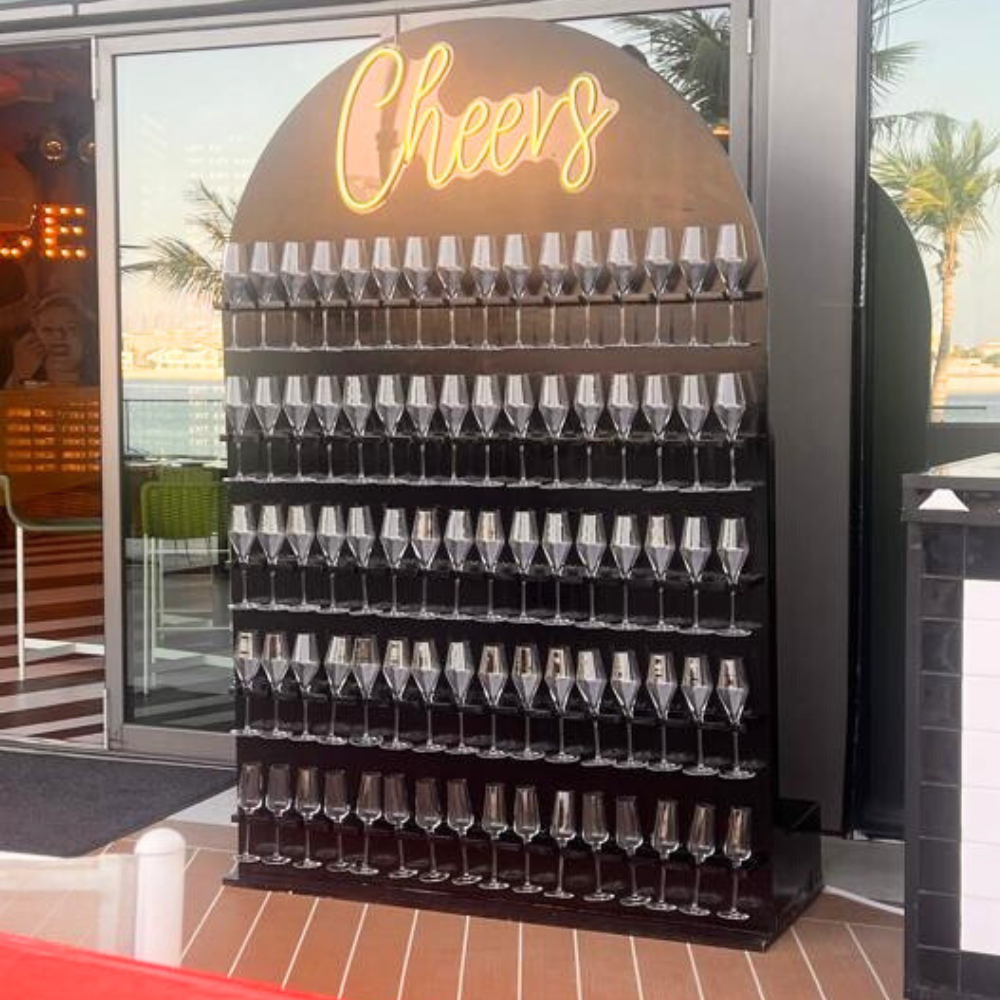 Cheers- LED Neon Sign displayed among wine glasses, perfect for creating a lively atmosphere at parties or events, requiring electric connection.