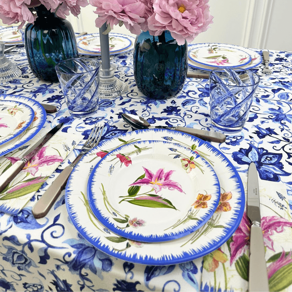 A table set with plates, flowers, and a vase, showcasing the Summer Florals Polyester Linen Tablecloth from Party Social. Elevate your dining experience with this elegant and reusable tablecloth.