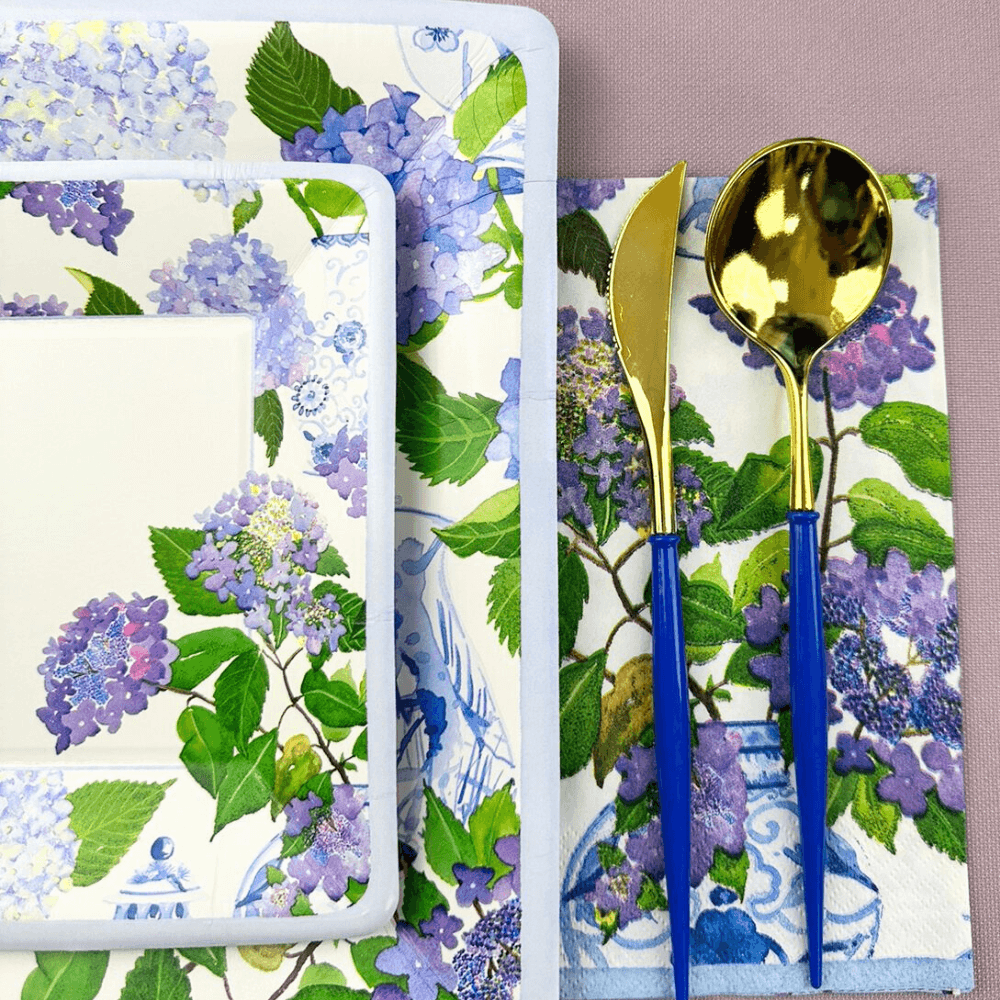 Hydrangeas and Porcelain Paper Guest Towel Napkins, 15 per package, displayed on a table setting with a spoon and plate on a napkin.