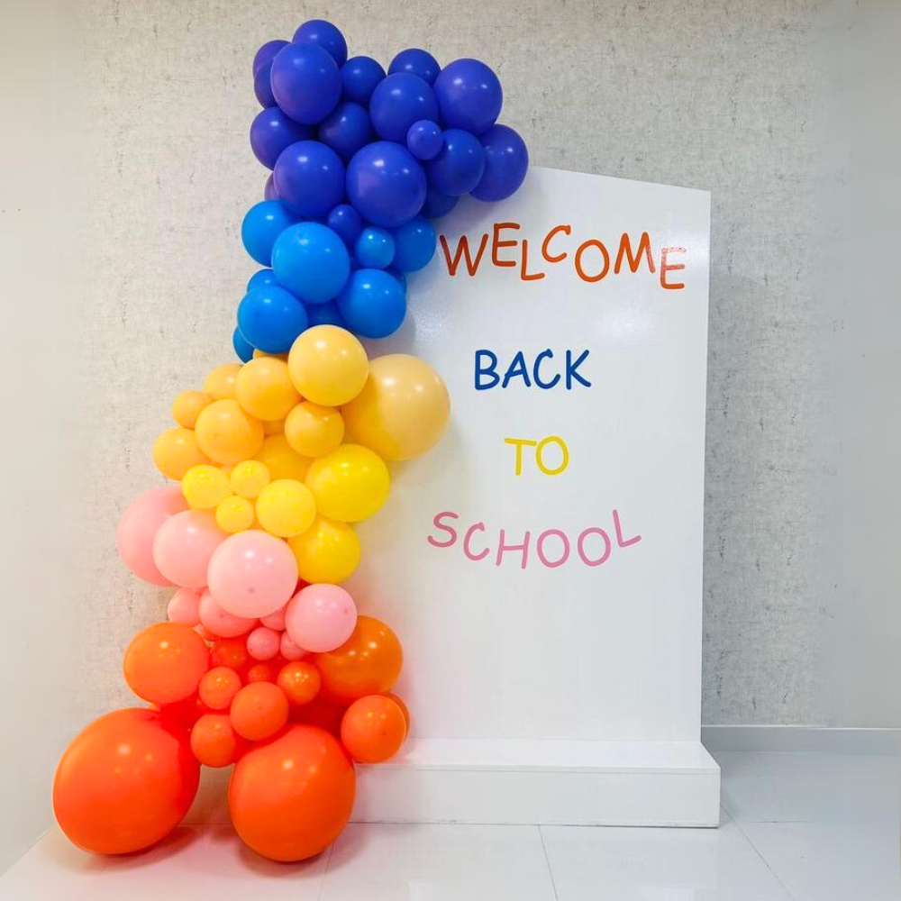 Angled Wall Balloon Backdrop for events, featuring various balloons next to a sign; ideal for celebrations like birthdays or showers, customizable for any occasion.