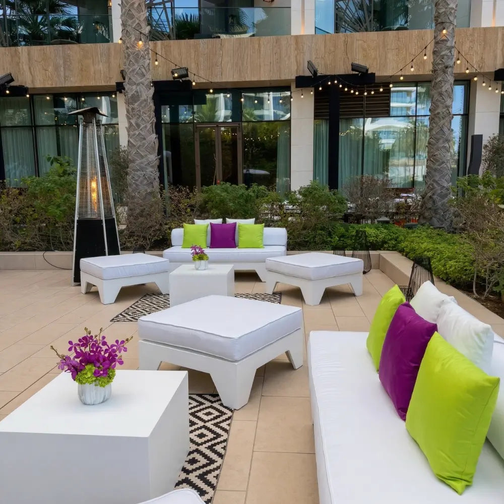 White ottoman seater in a modern outdoor lounge setup with matching sofas and geometric rug, perfect for event rental or purchase from Party Social.