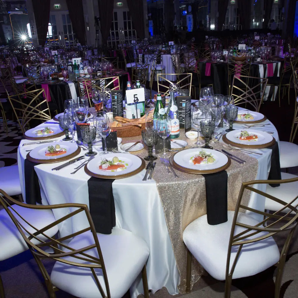 ROUND TABLECLOTH SATIN elegantly drapes a banquet table, set for a gala with fine dining settings, showcasing Party Social&