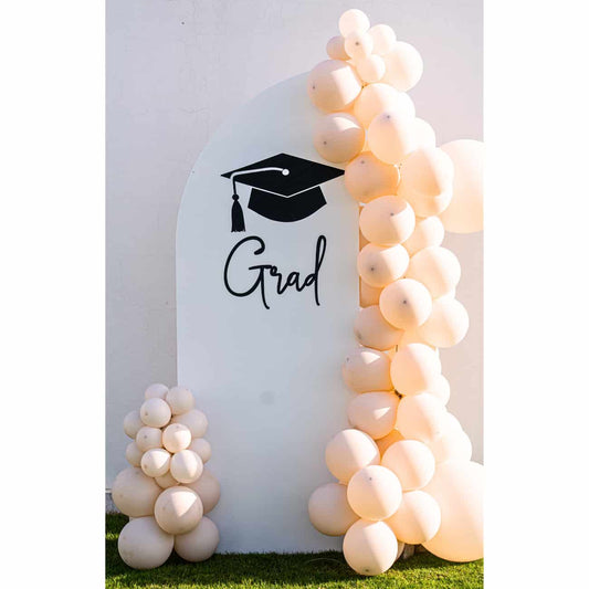 Sweet Soirée Balloon Arrangement featuring a white arch backdrop with Grad text and cream balloon garland, perfect for elevating graduation celebrations.