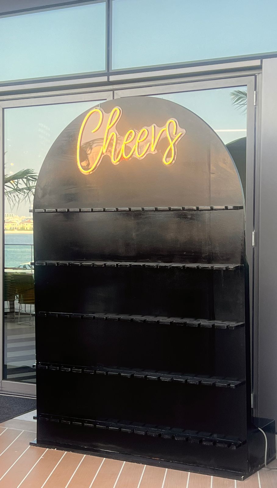 CHAMPAGNE WALL display featuring a sleek black case with a yellow neon sign, ideal for event decor from Party Social.