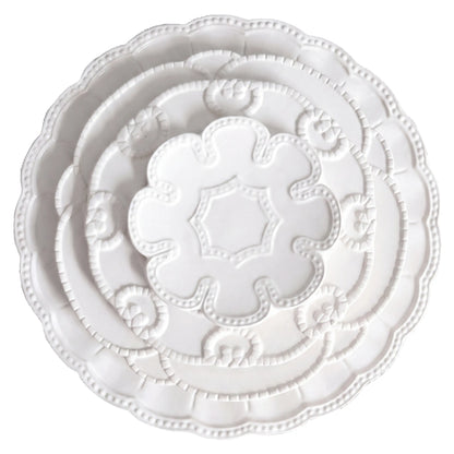 White Embossed Collection: Stack of three decorative plates, featuring scalloped edges and floral patterns, ideal for elegant event settings from Party Social.