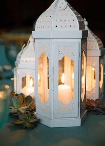 WHITE MOROCCAN LANTERNS with lit candles inside, showcasing various sizes suitable for event decor. Candles not included.