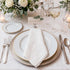 Set of four white linen dinner napkins with floral embroidery and scalloped edges, enhancing elegant table settings.