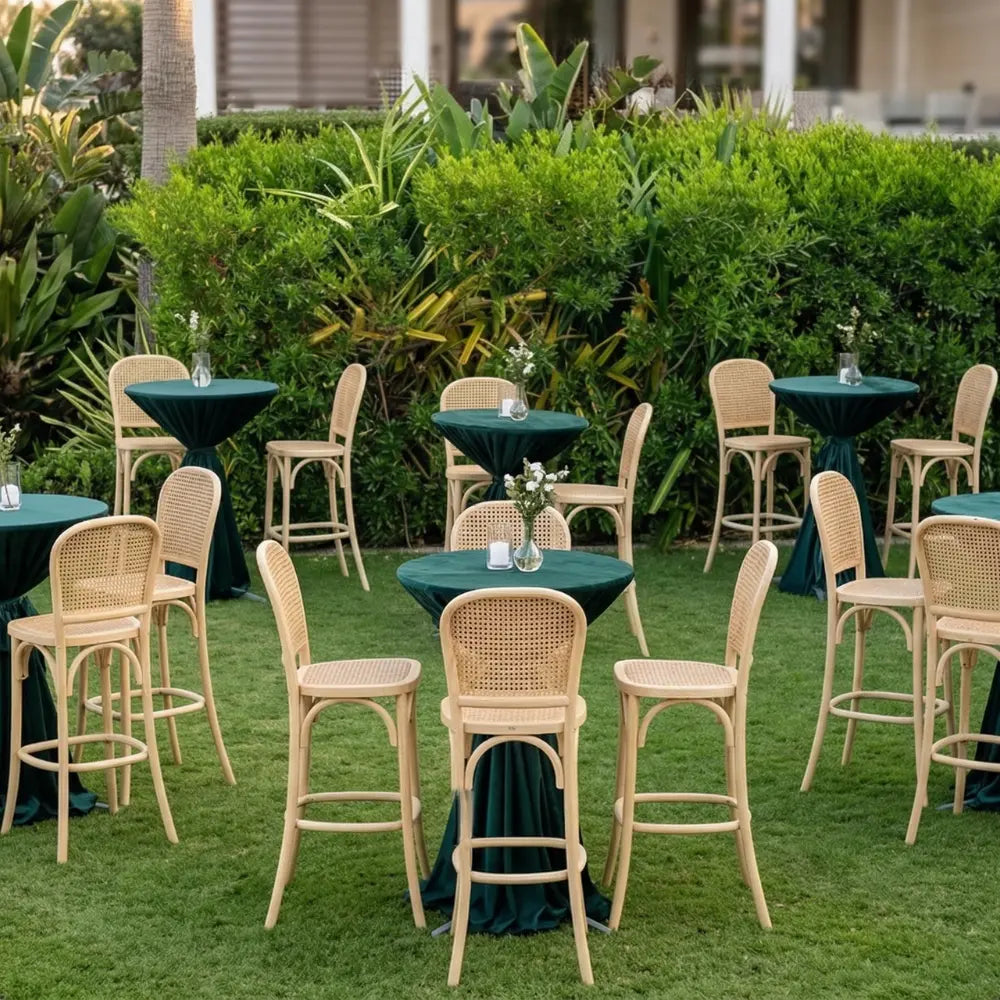 Wood Rattan Stool with hand-woven cane backrest and seat, set in a garden-style reception area with highboy tables and floral arrangements.