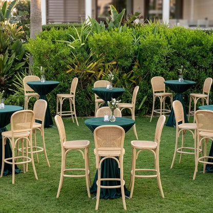 Wood Rattan Stool with hand-woven cane backrest and seat, set in a garden-style reception area with highboy tables and floral arrangements.