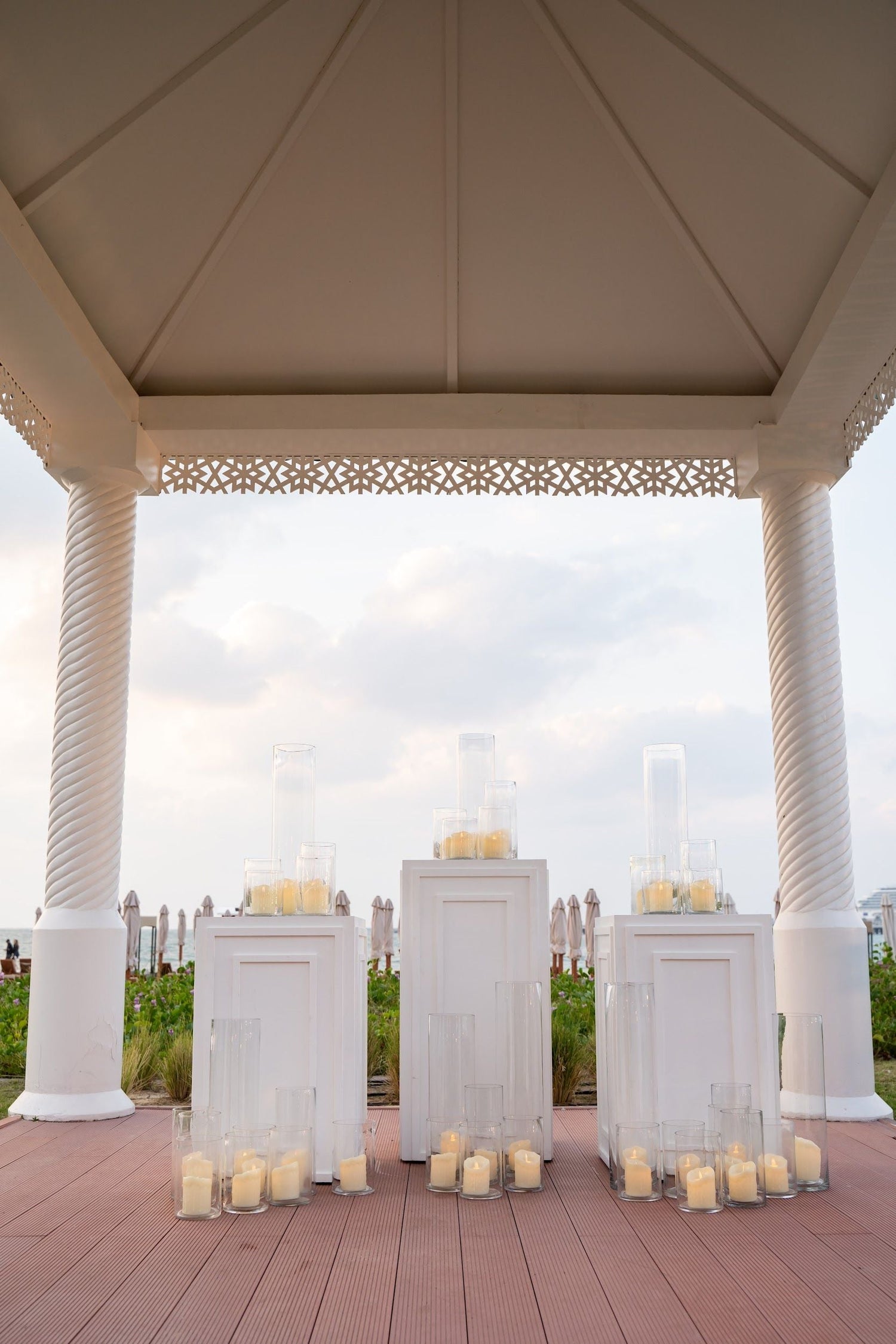 Square Lined Podiums with pillar design, surrounded by candles on a deck, ideal for weddings and birthday celebrations, available in two sizes.