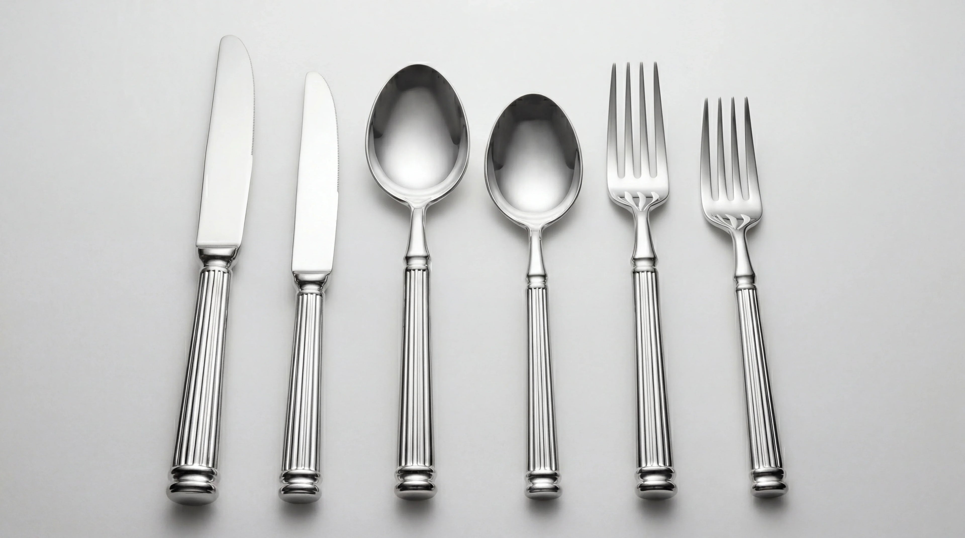 CUTLERY MODERN SILVER: A polished silverware set with two knives, spoons, and forks, ideal for elegant events and refined celebrations.