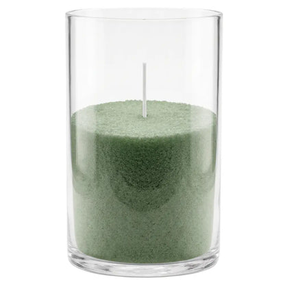 A green wax candle in a clear cylindrical glass container with a single white wick, shown against a plain white background.